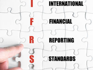 Hand of a business man completing the puzzle with the last missing piece.Concept image of Business Acronym IFRS as International Financial Reporting Standards