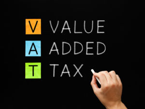 Hand writing VAT - Value Added Tax with white chalk on blackboard.