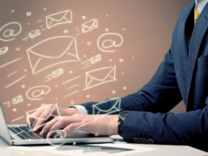 An office worker sending emails and communication with clients with the help of a portable laptop on desk concept