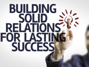 Business man pointing to transparent board with text: Building Solid Relations For Lasting Success