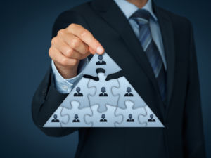 CEO leadership and corporate hierarchy concept - recruiter complete team represented by puzzle in pyramid scheme by one leader person (CEO).